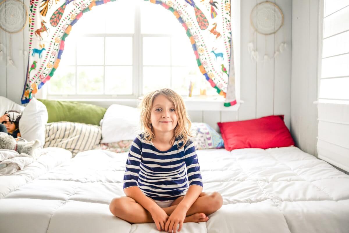 Happy little girl sitting on the bed