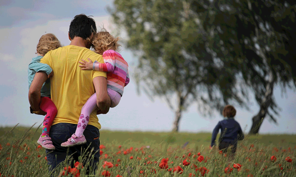 father in field with kids