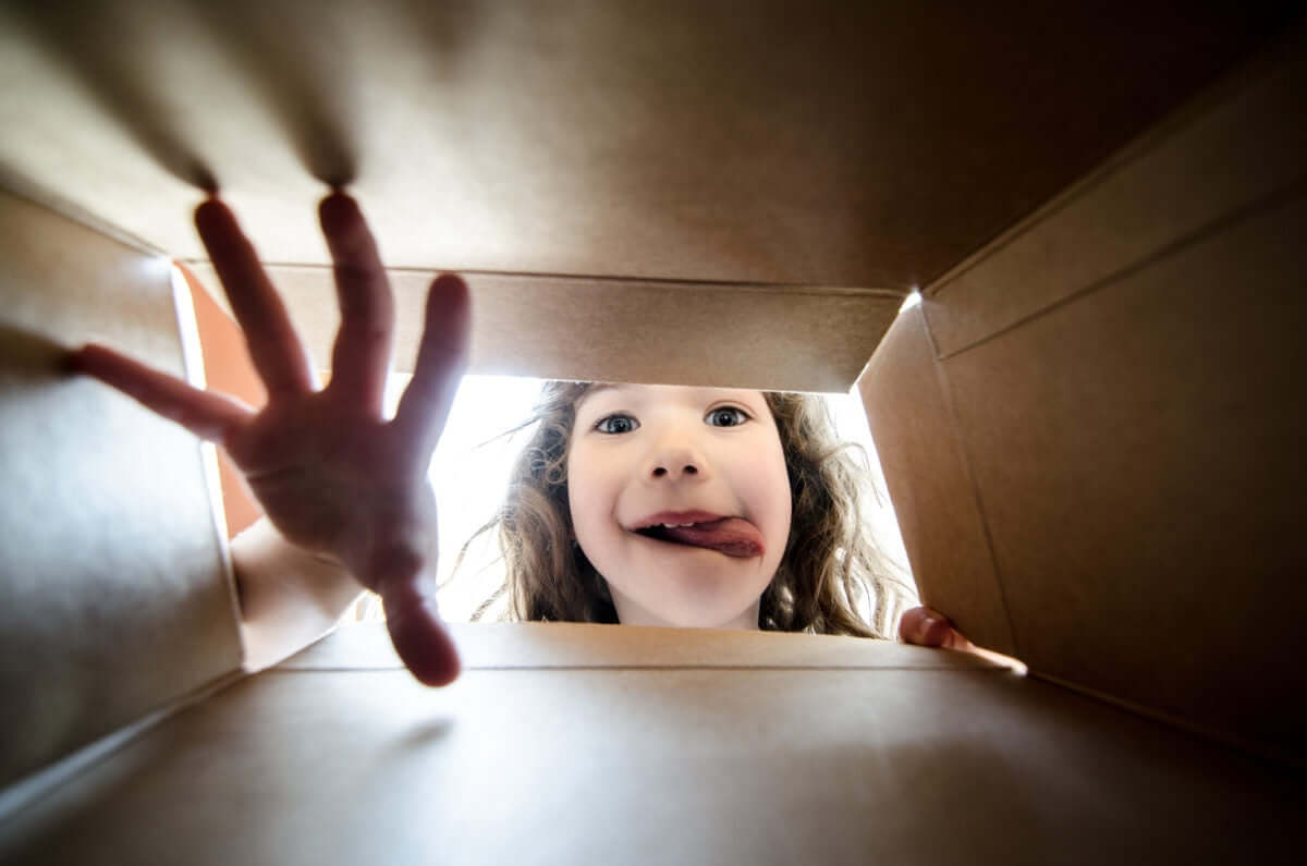 From under the box, a girl sneeking with hand inside