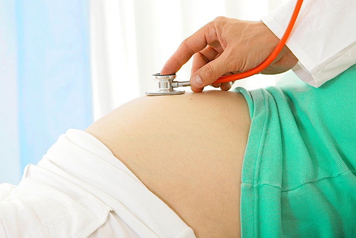 doctor checking pregnant women belly