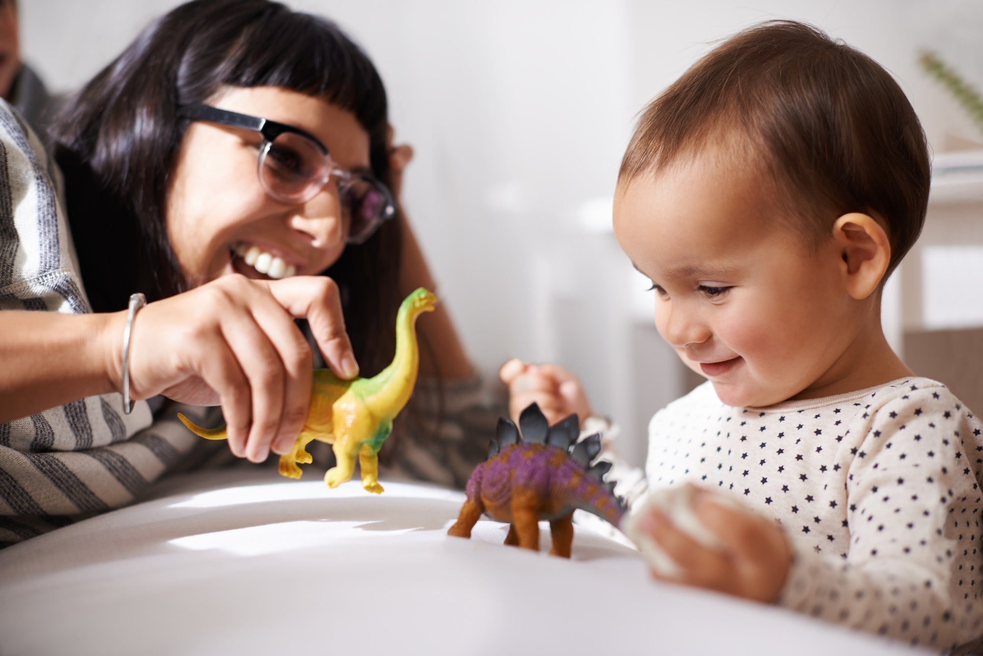 mom and child playing with colorful toy dinosaurs