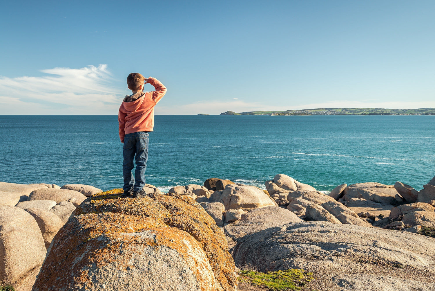 A child standing on the sea shore and watching waves