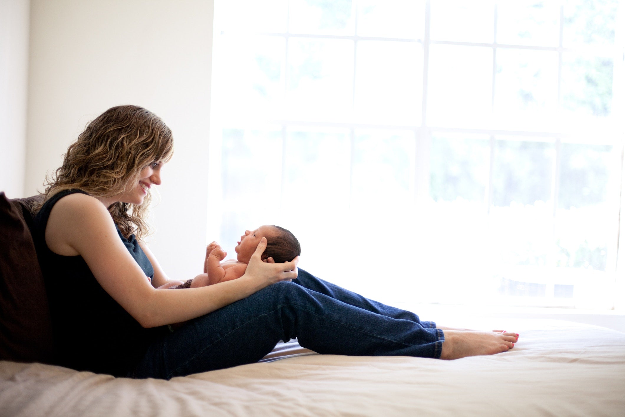 Young mother holding her newborn son in bed