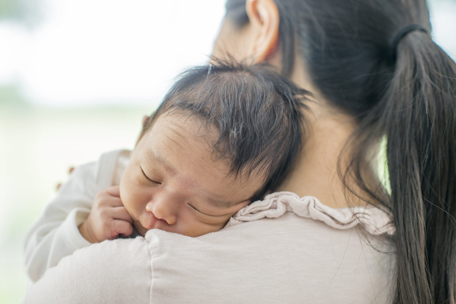 mother holding baby resting on shoulder