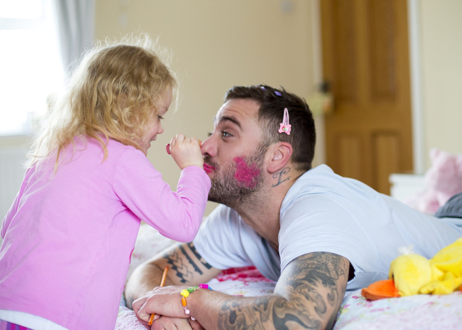 little girl applying lipstick on her father