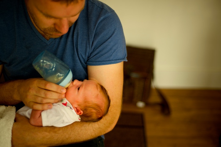 father feeding cute little baby daughter with milk bottle