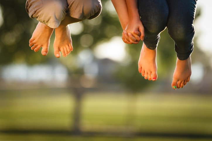 legs of boy and girl jumping in a garden