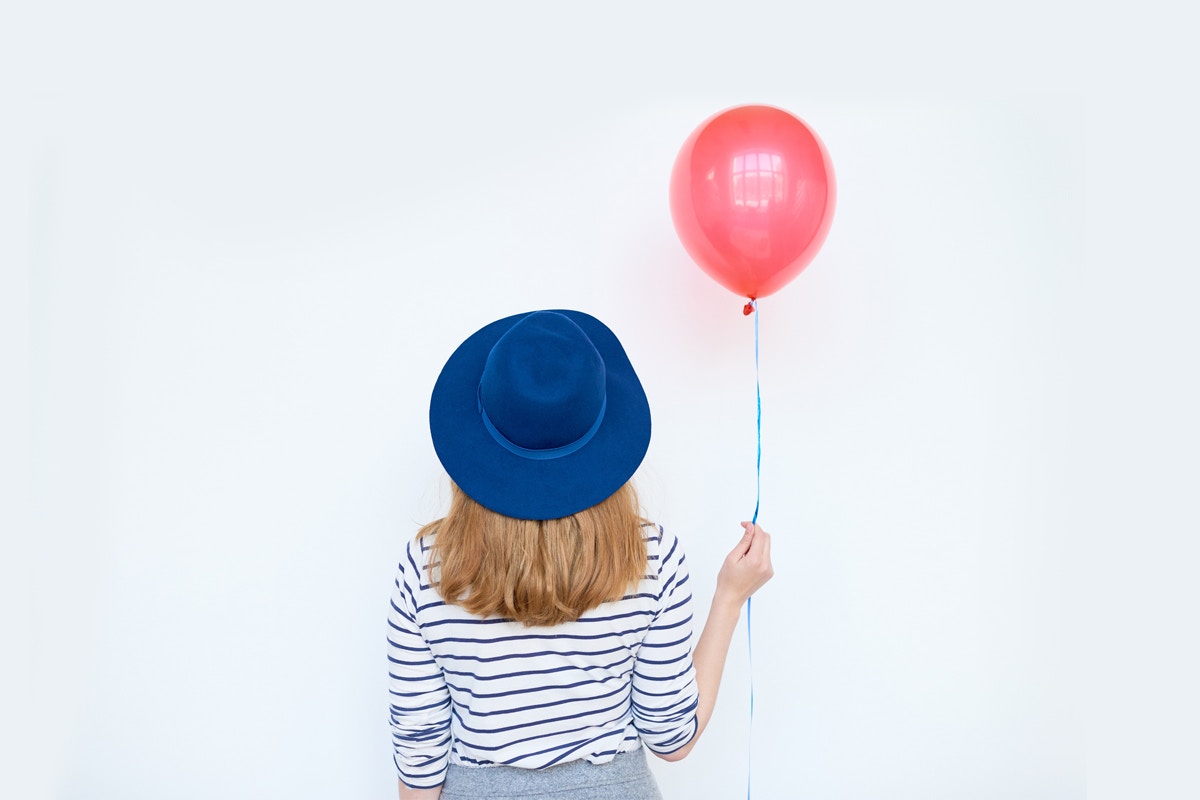 woman in hat holding balloon
