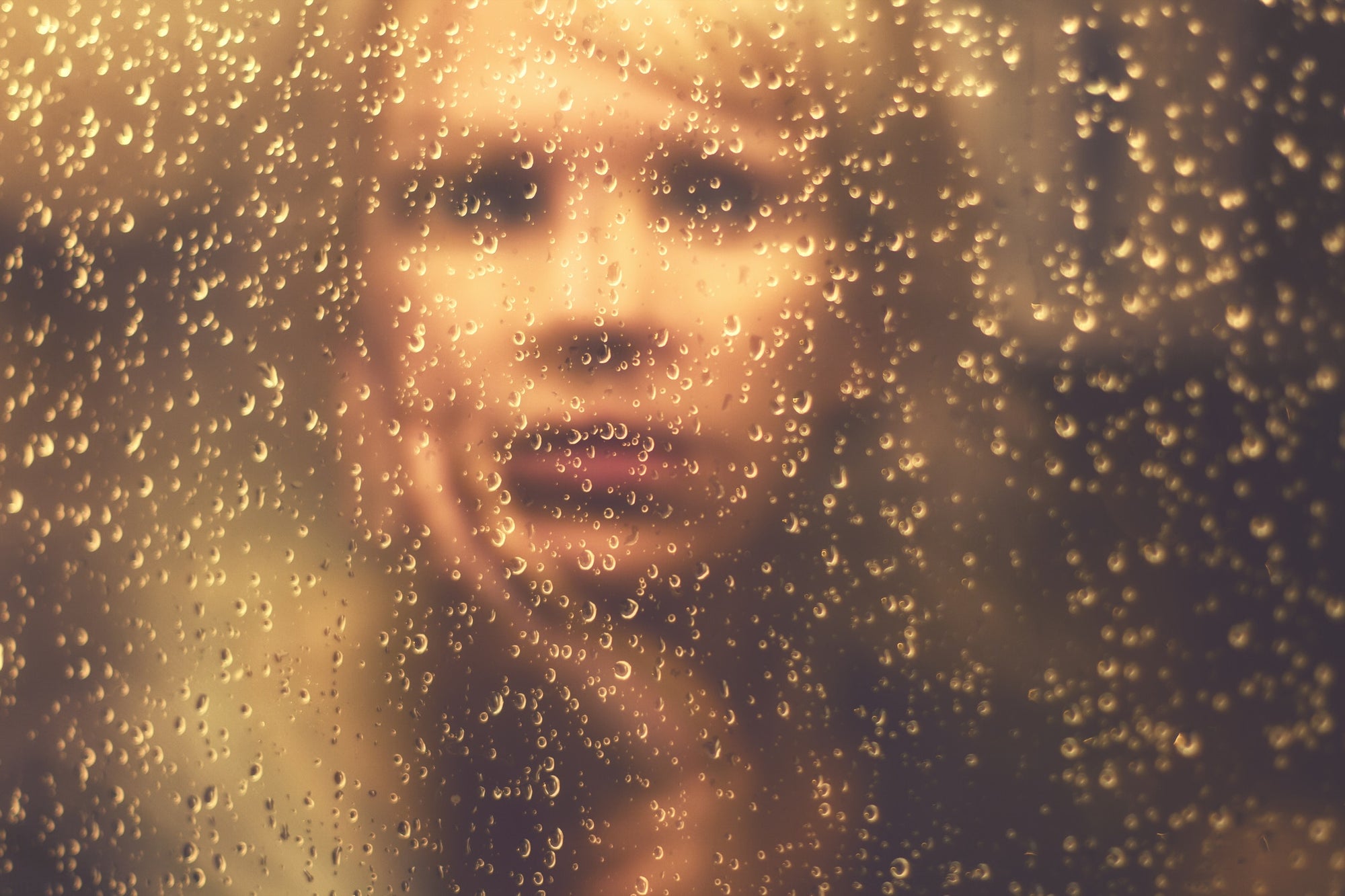 Woman Looking Through Window Covered With Raindrops