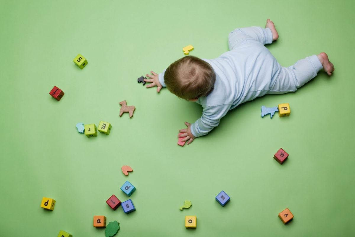 toddler crawling on the floor playing with building blocks toys