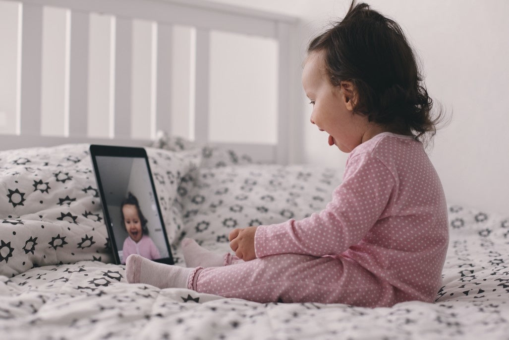 baby sitting on the bed communicates on video call