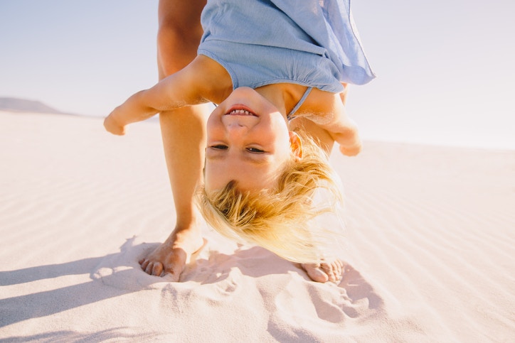 parent holing young blonde girl upside down