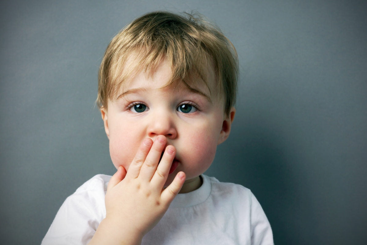 little boy covering his mouth with hand