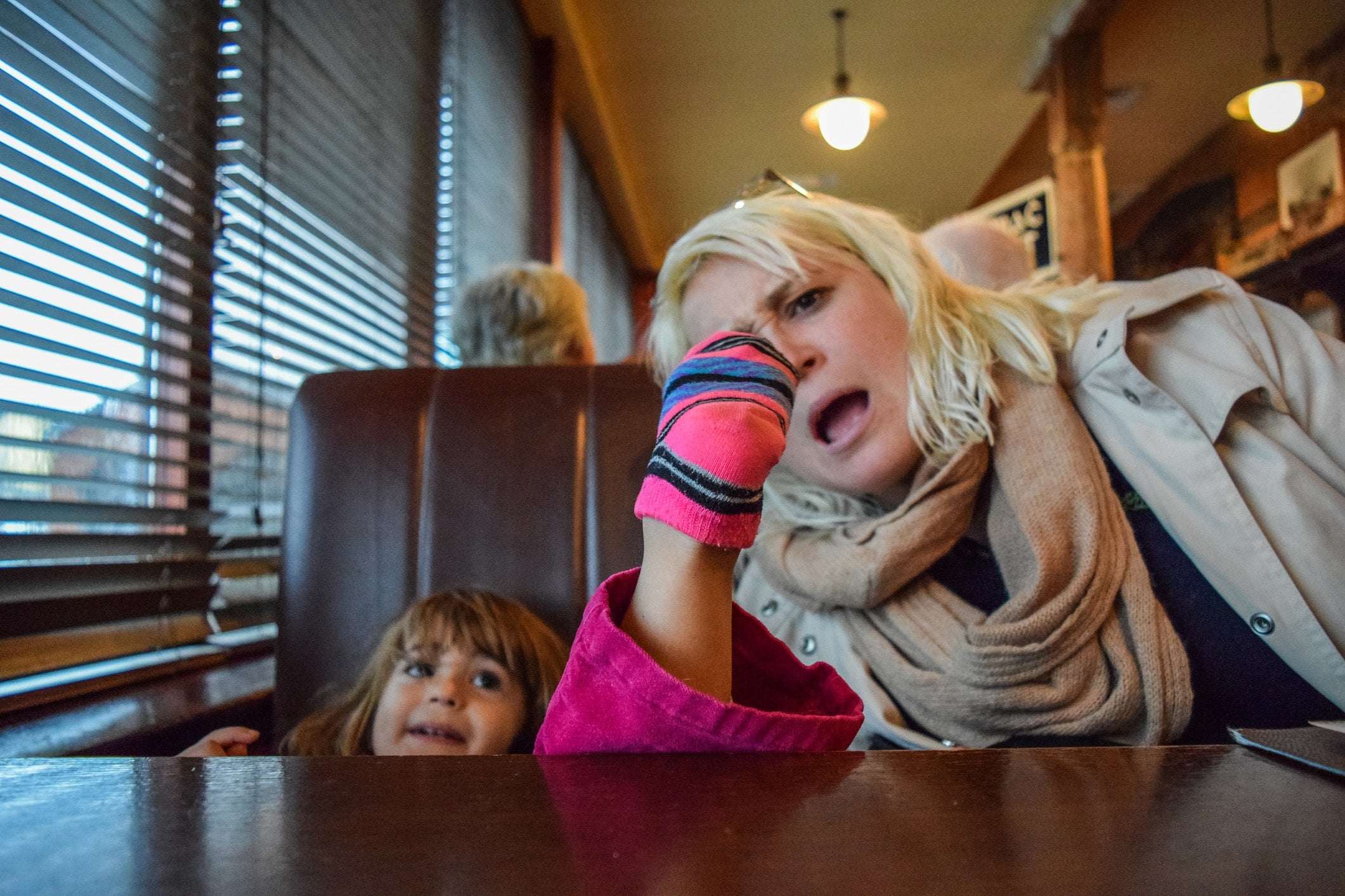 mother looking at her little girl's sock and sitting on the cafe