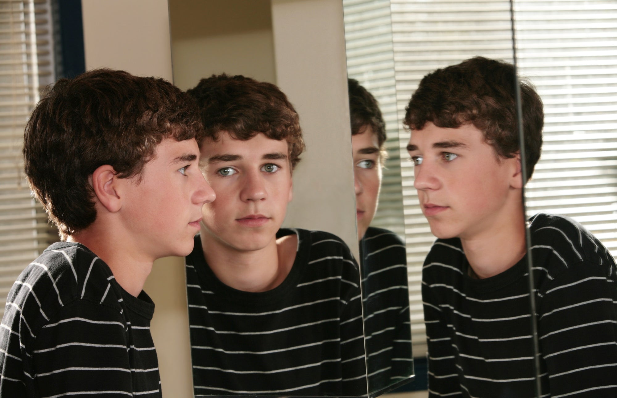 a young boy looking at his reflections