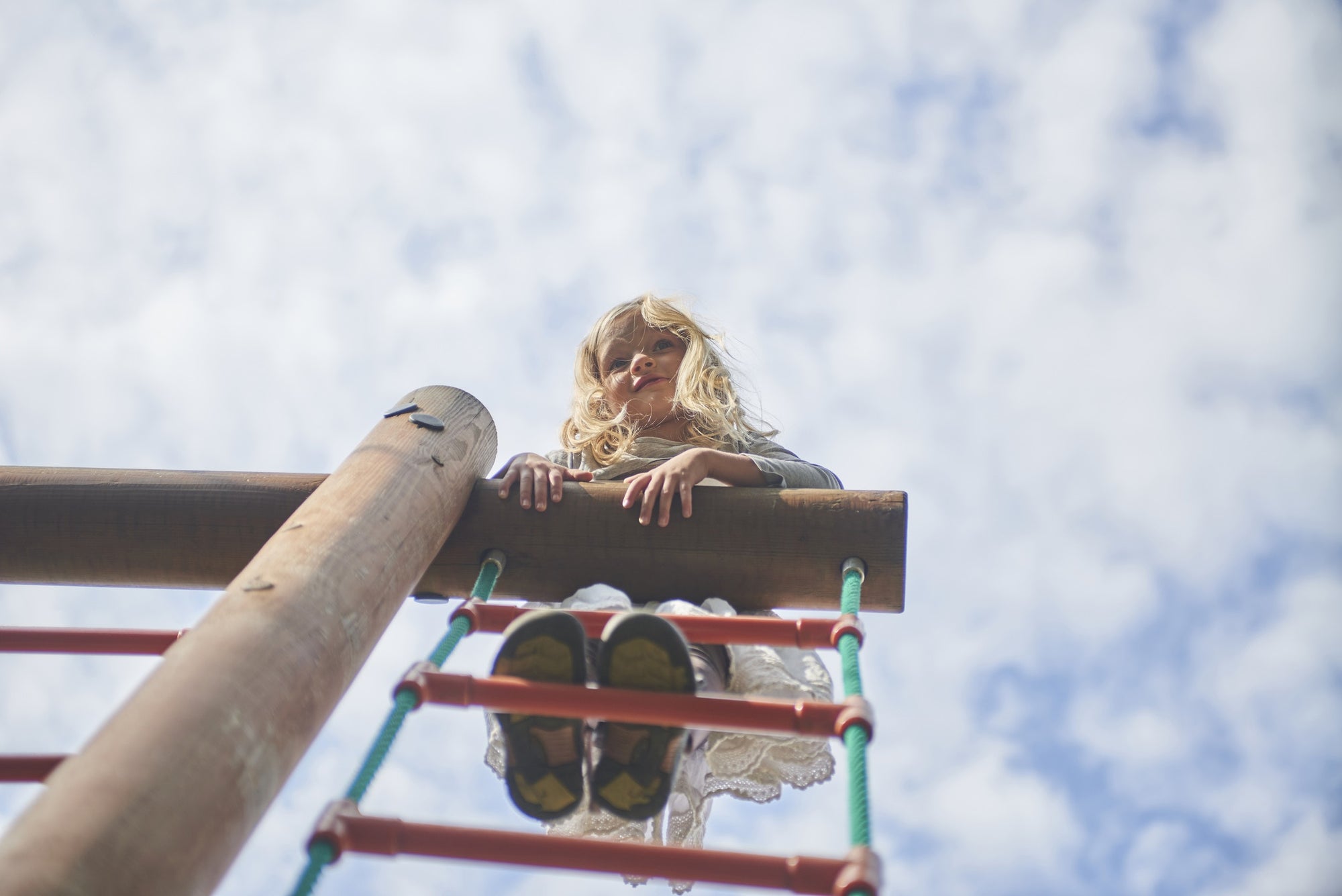 Young girl standing at top of ladder in playground