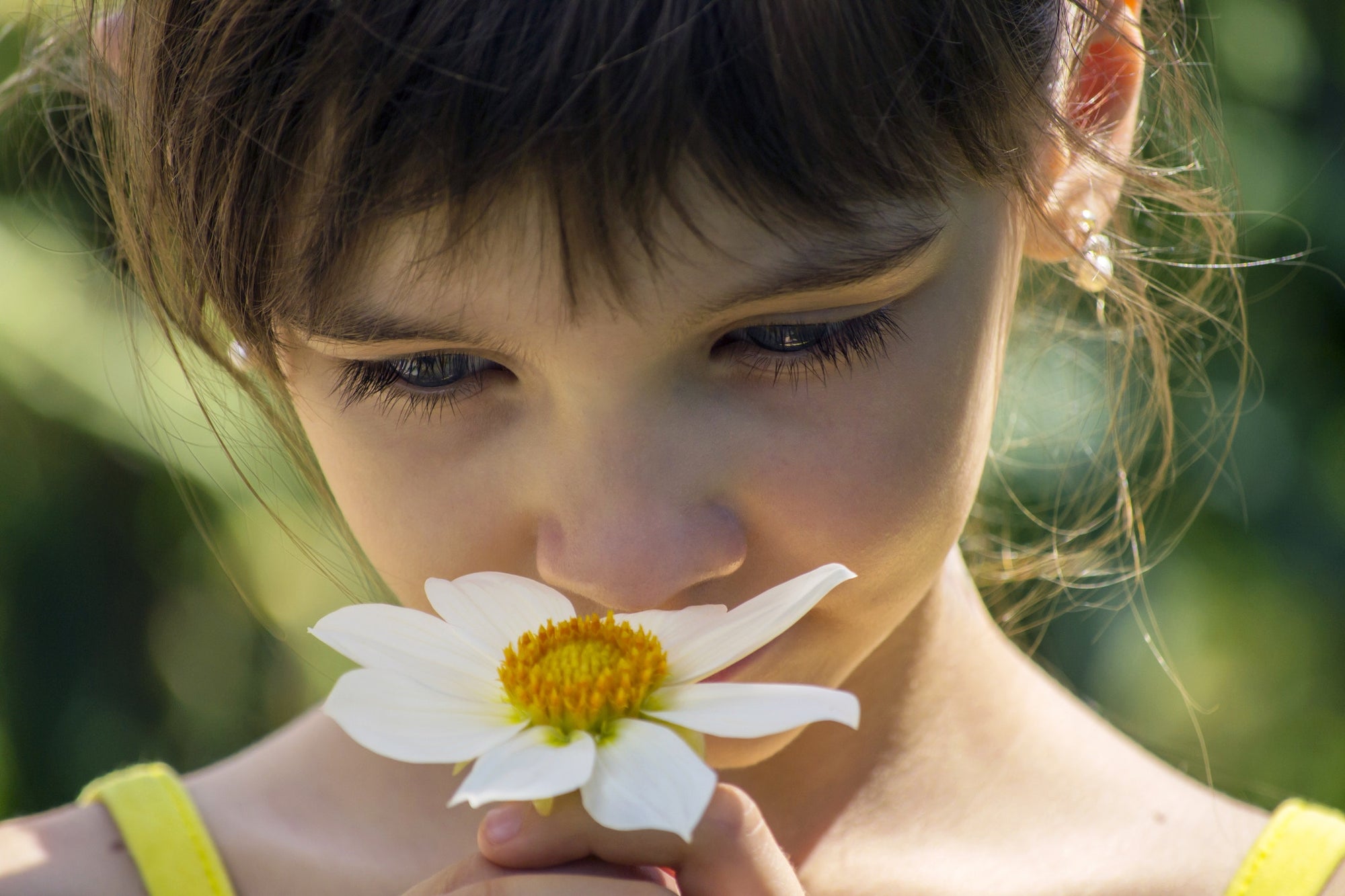 A little girl smelling flowers in a garden