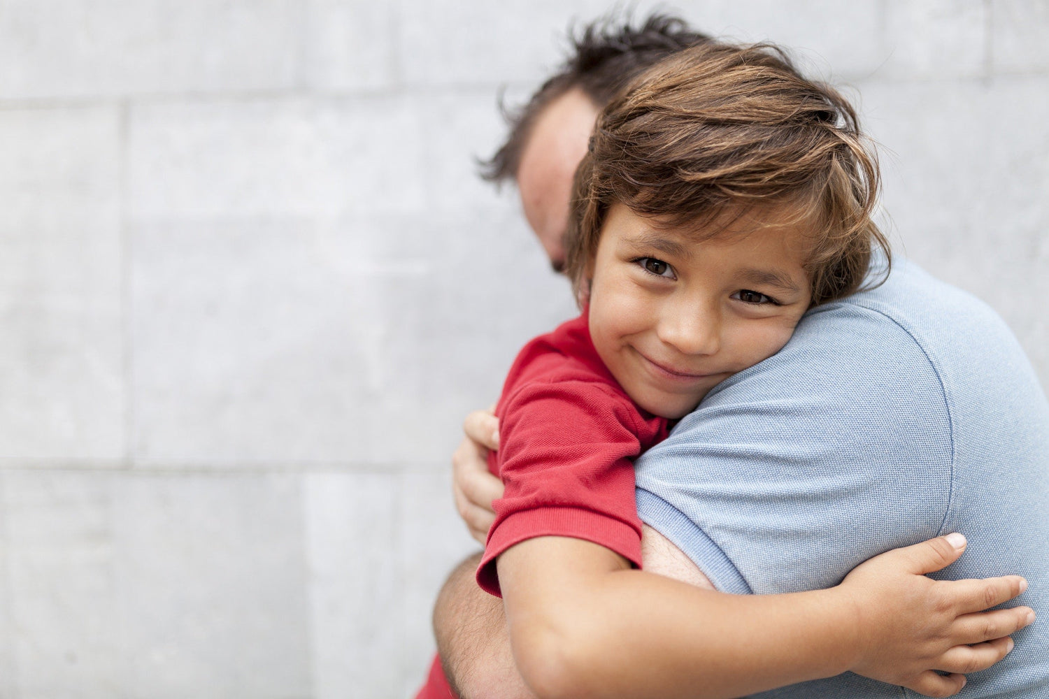 father holding young kid resting on shoulder and smiling