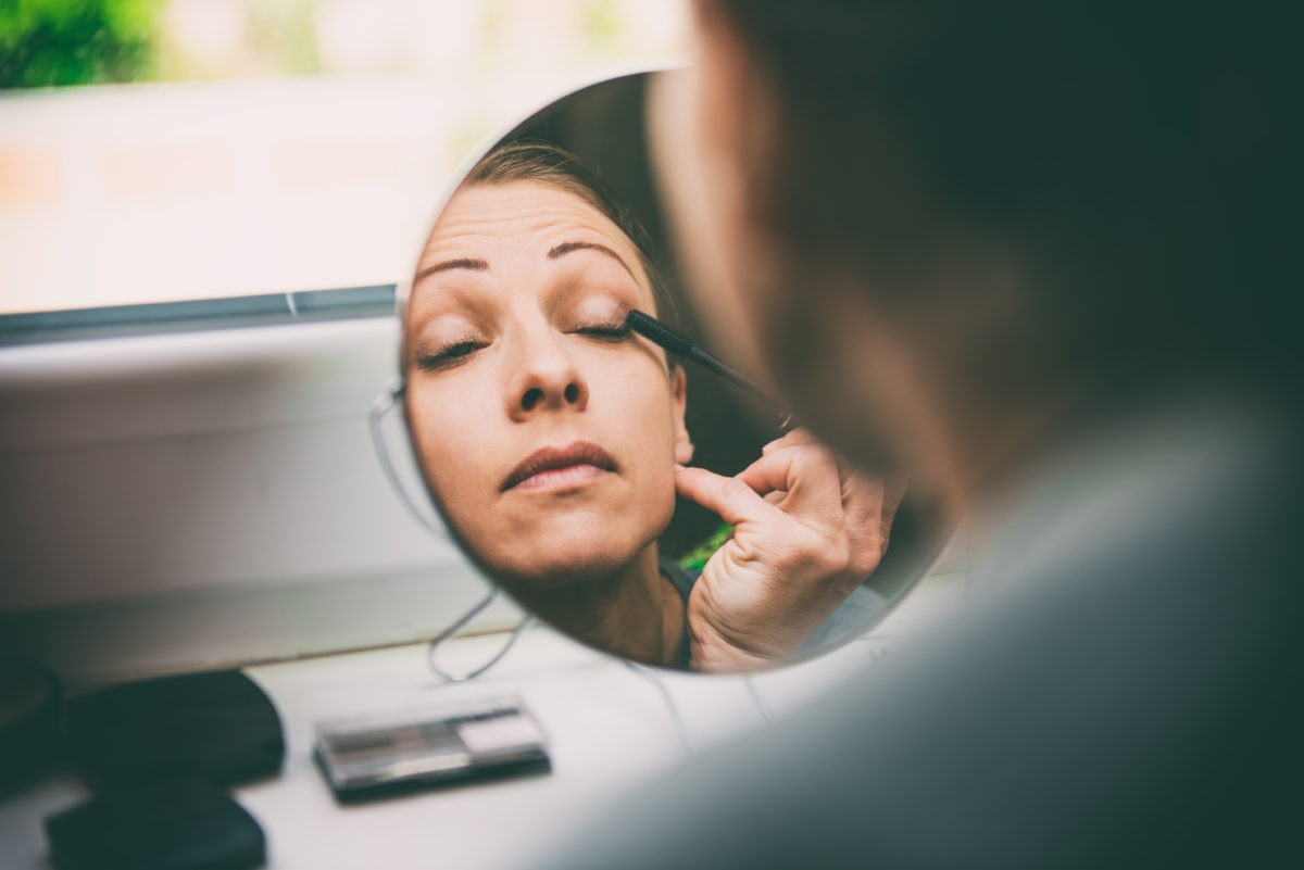 Lady doing makeup on a circle mirror