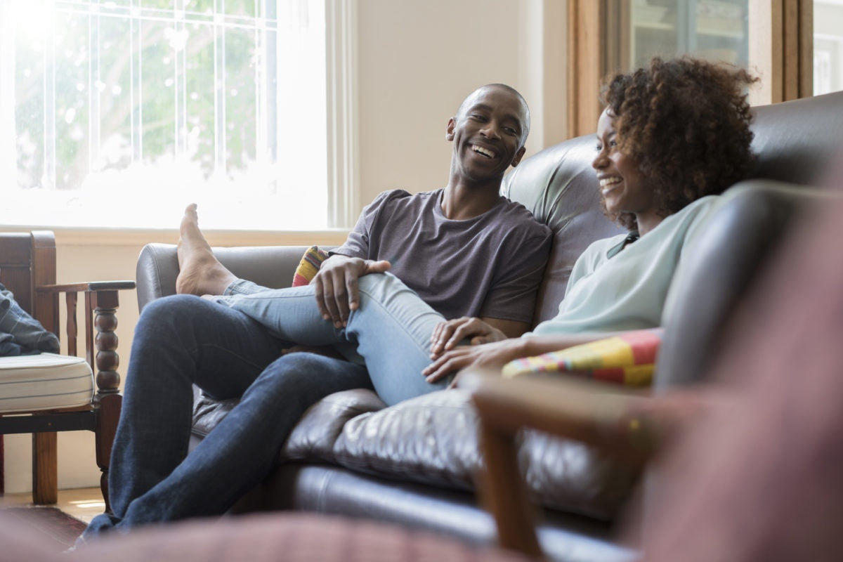 Two guys are felling happy , laughing each other by sitting on a sofa