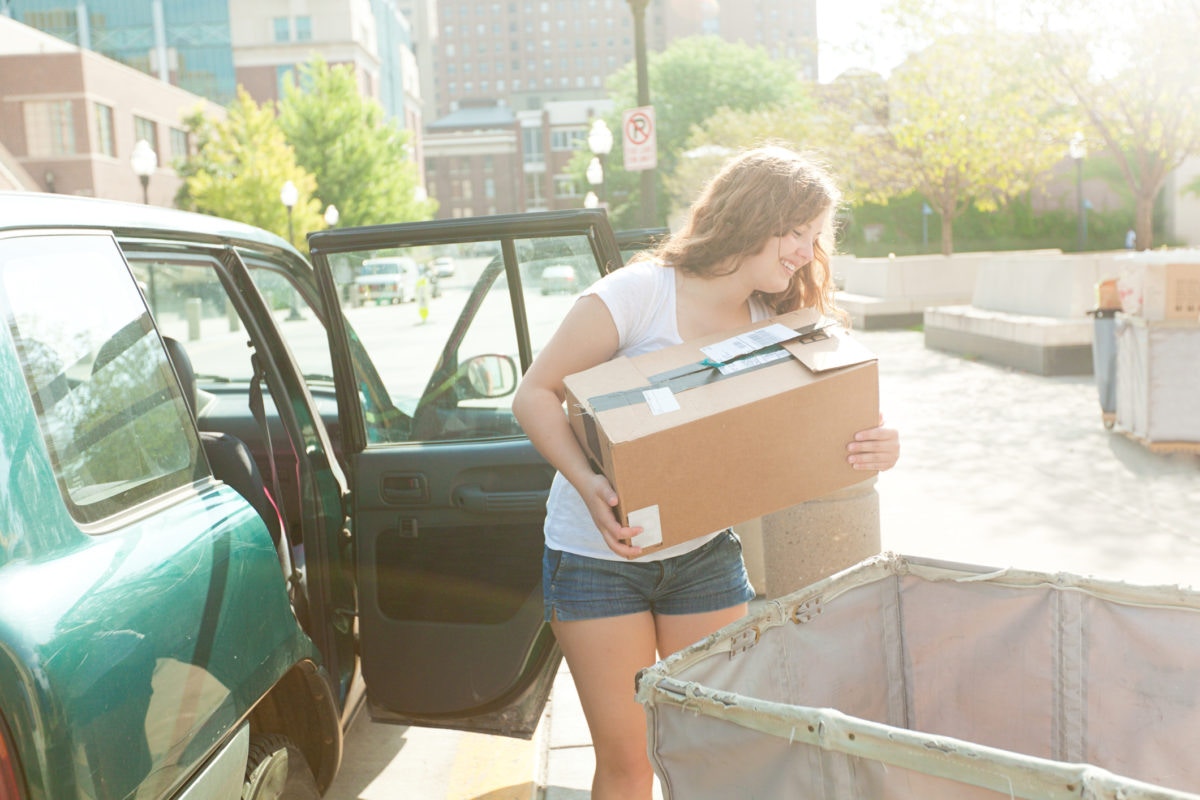 happy woman carrying cardboard moving box