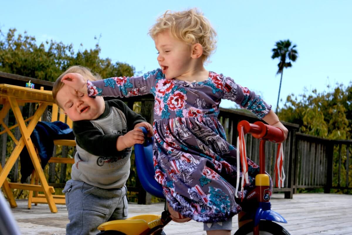 Two kids are playing while one is hitting to another's head