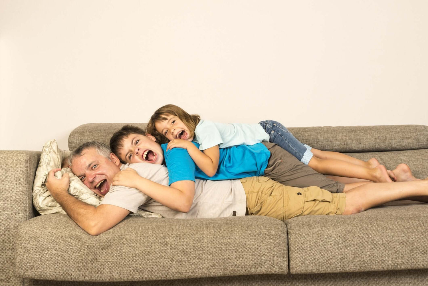 Father,son and daughter lying on top of each other