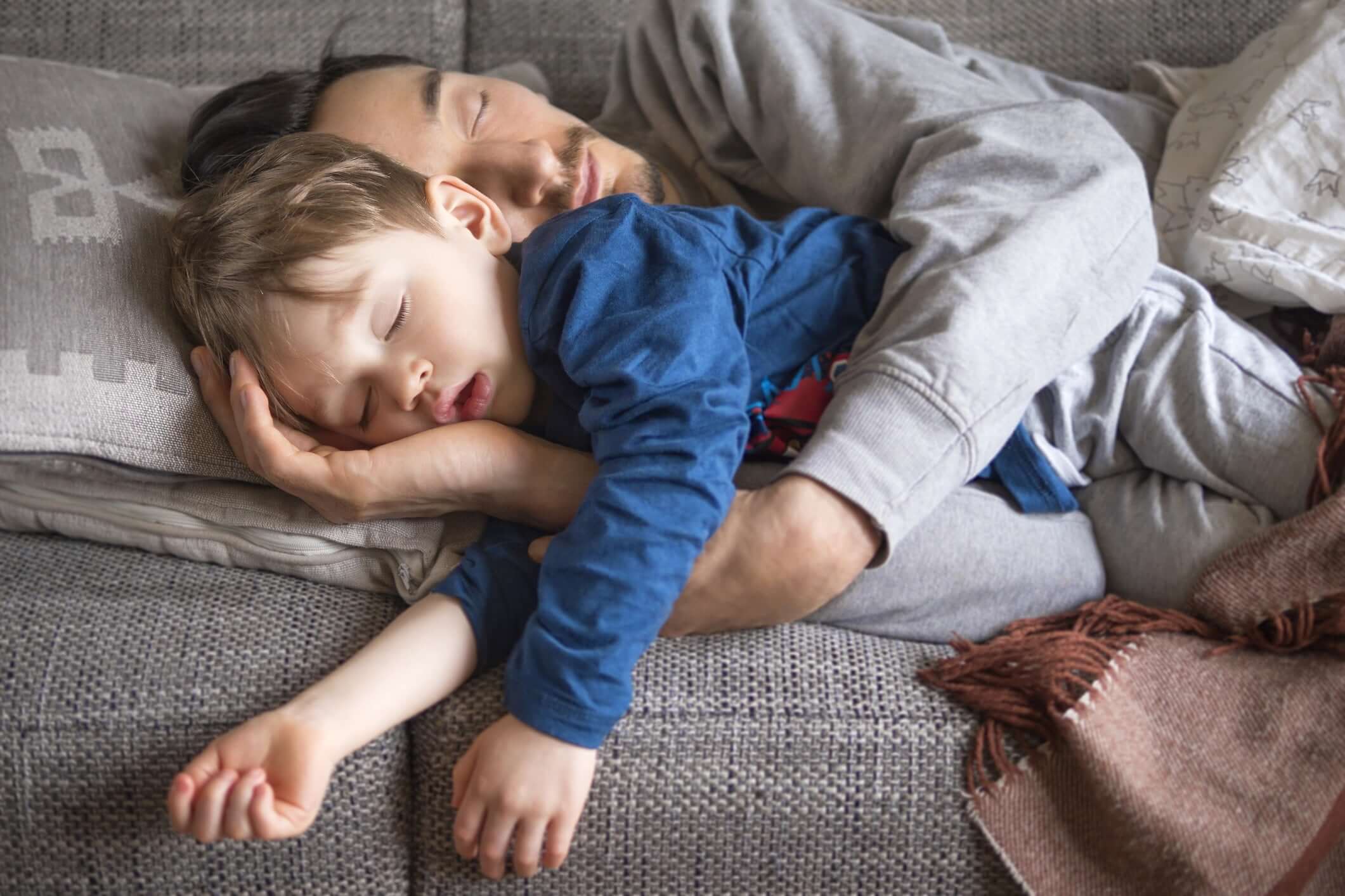 Father and baby boy sleeping on bed