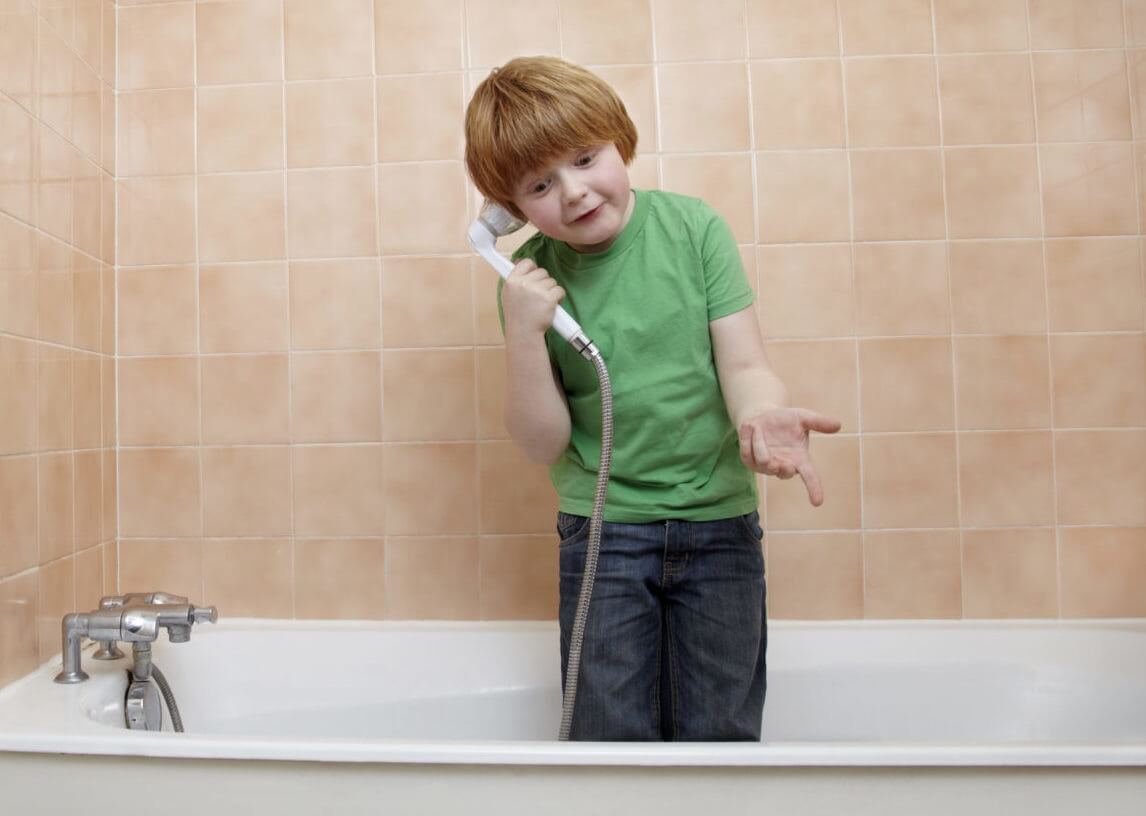 The boy standing in the bathtub and talking on the phone