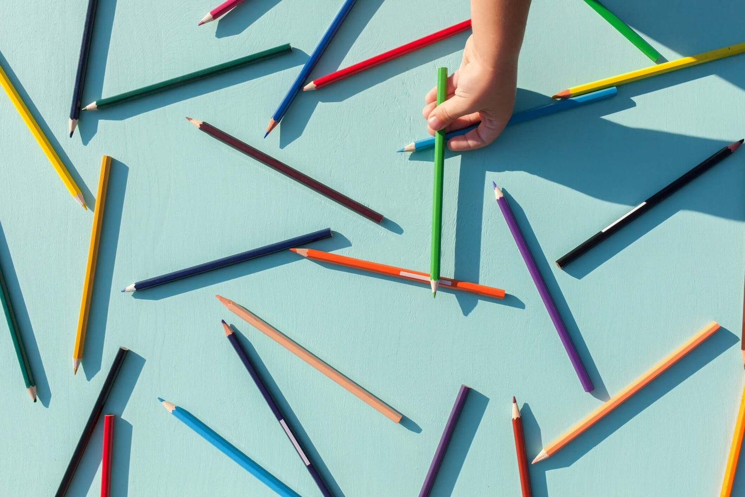 colored pencils scattered on blue background