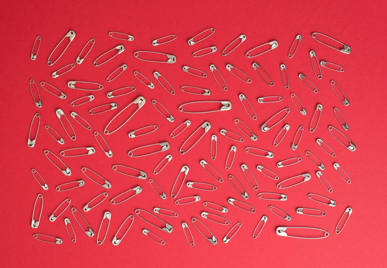 lots of safety pins over red background