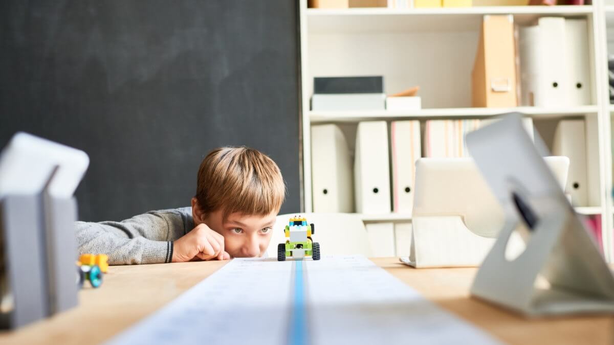 boy looking at his moving robotic toy car