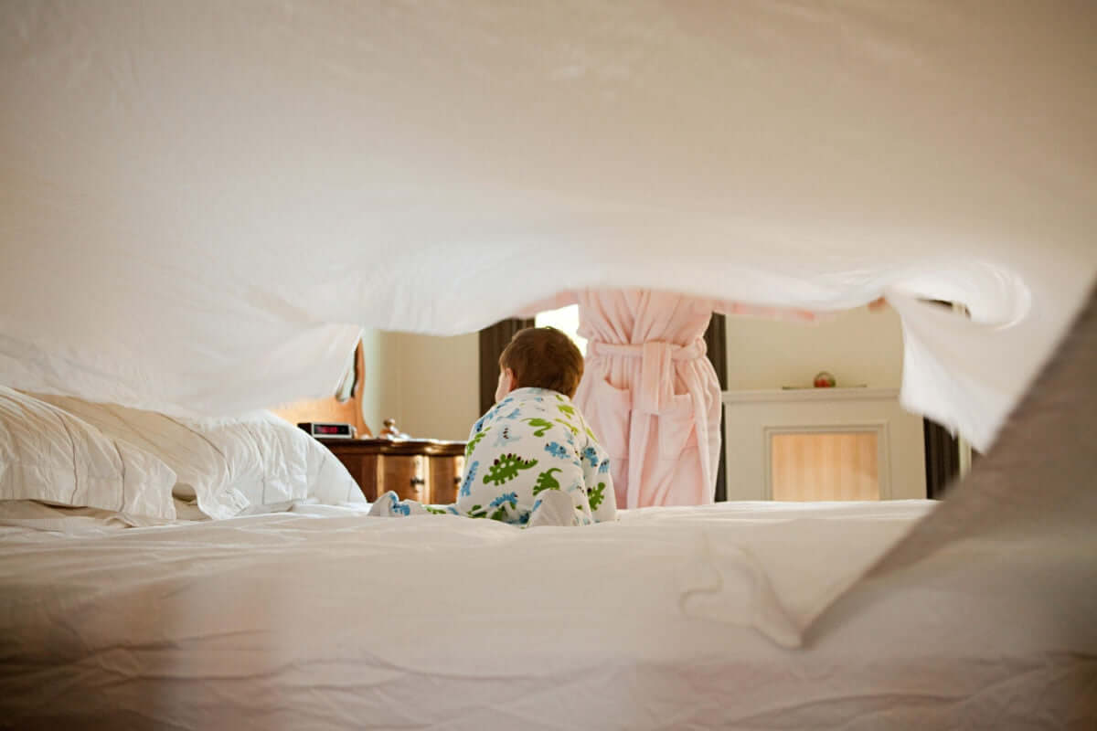 mother and baby son making bed