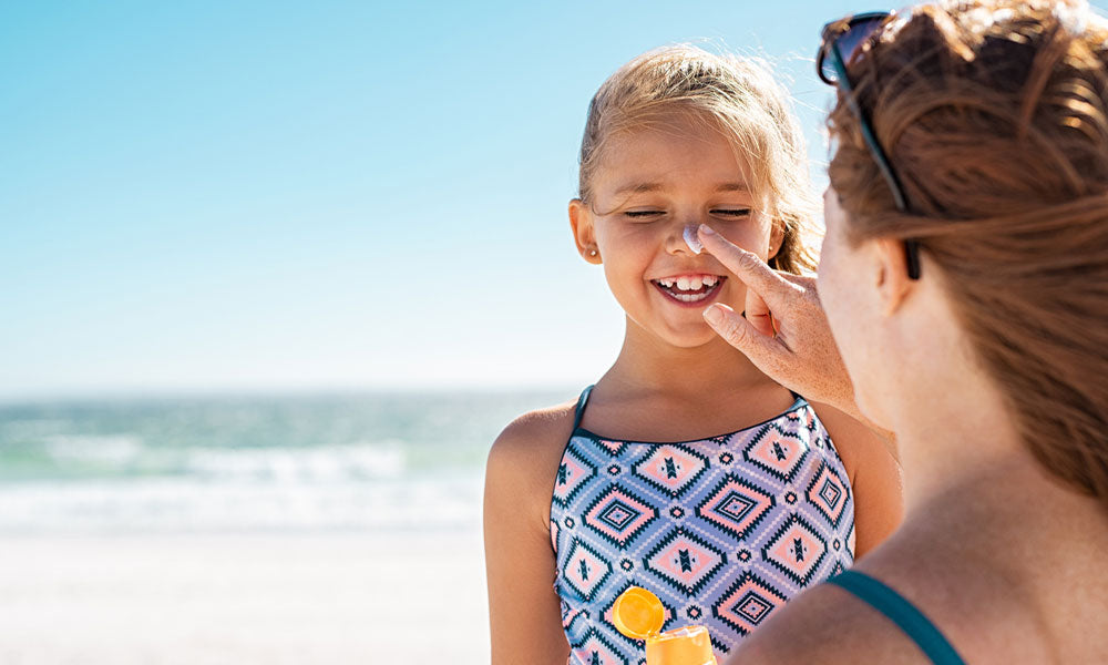mother applying suntan lotion on daughter