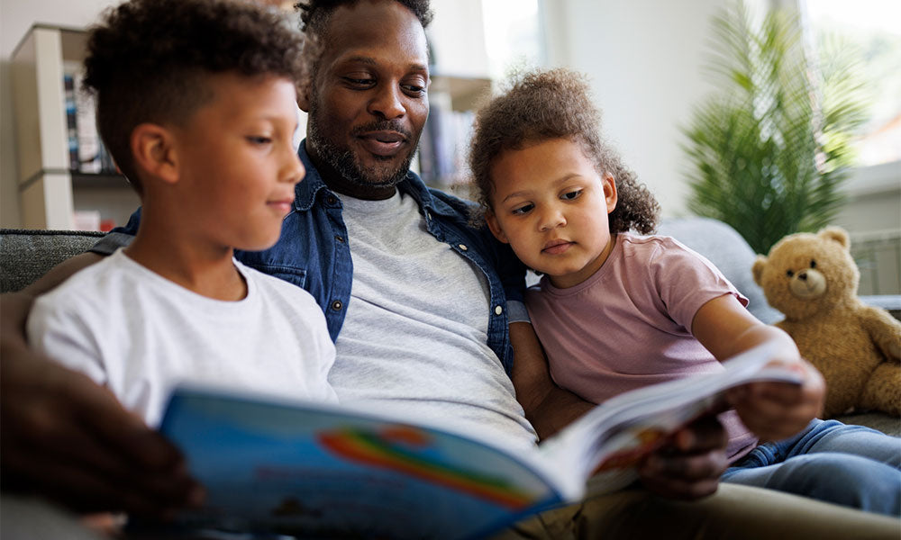 father reading book to son and daughter