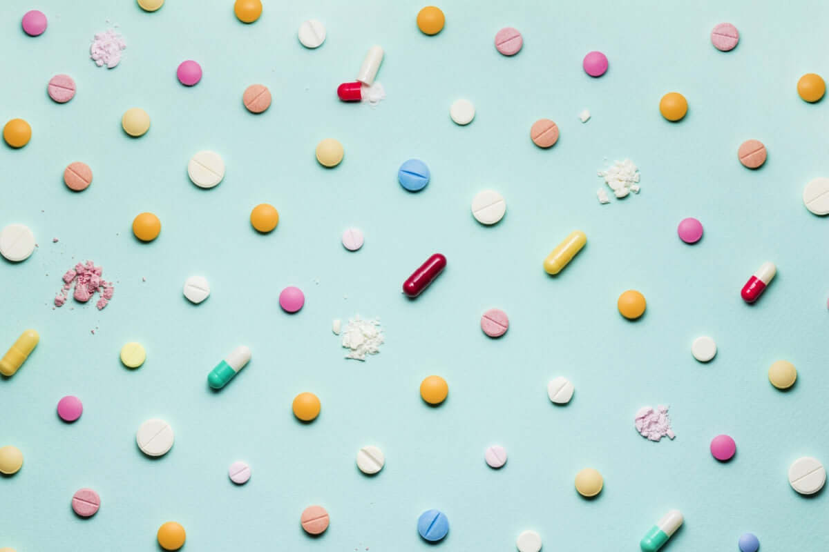 different type of pills arranged on light blue background