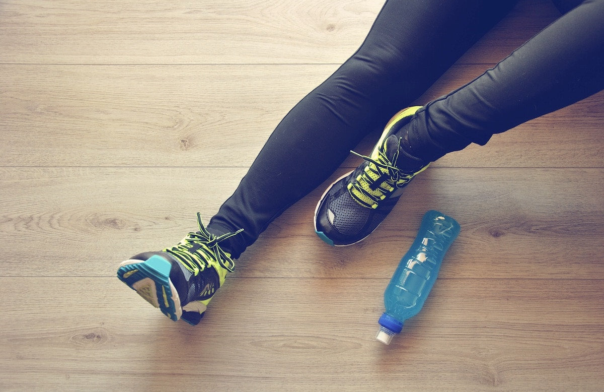woman in sweatpants just legs showing next to a water bottle