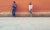 man and women standing in front of a brick wall few feet apart not looking at each other