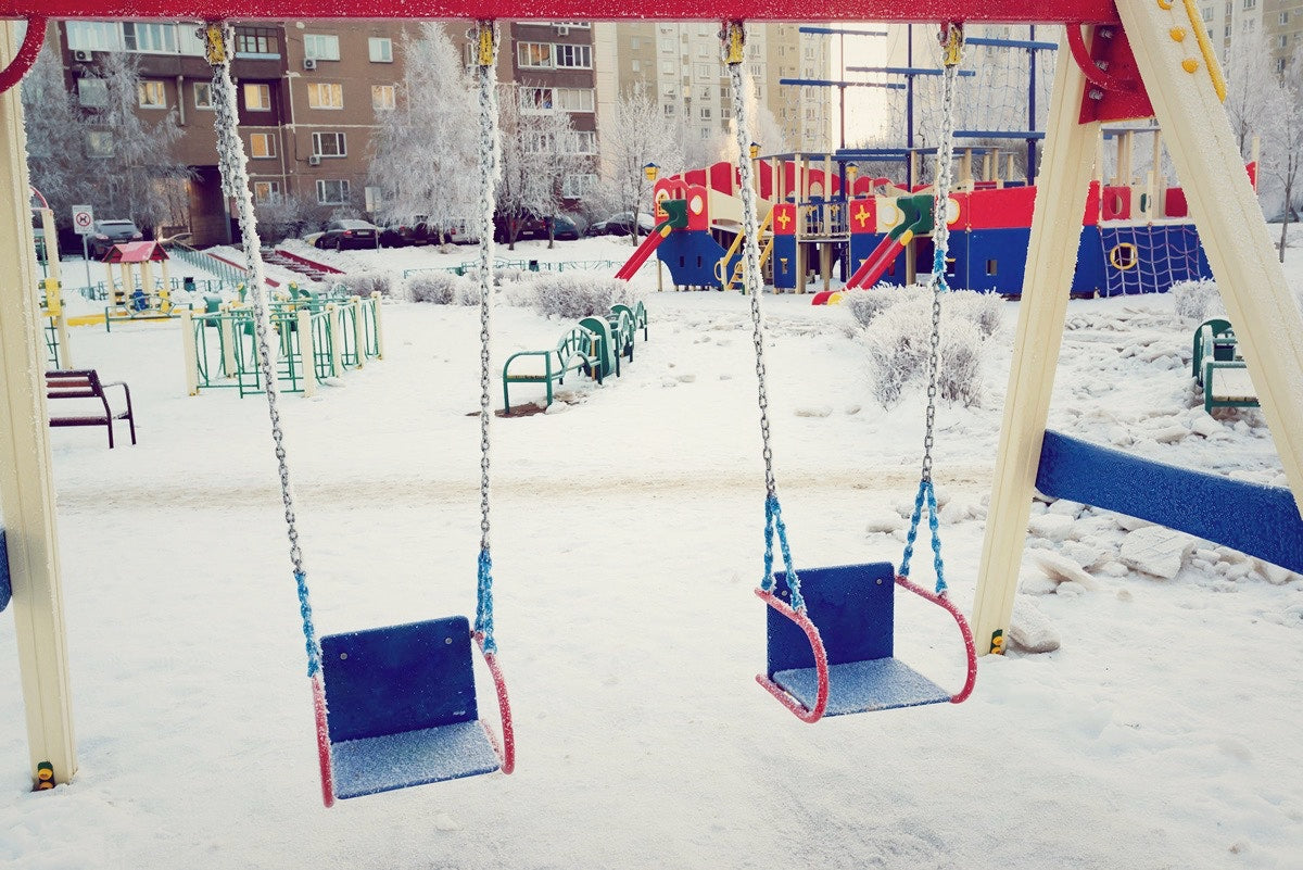 snow in a playground with two blue swings