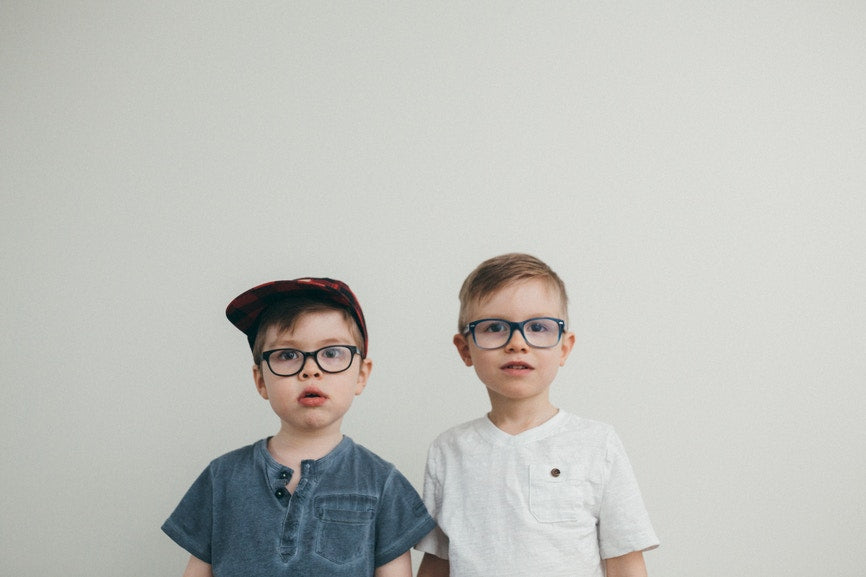 two boys with glasses one with hat one with out
