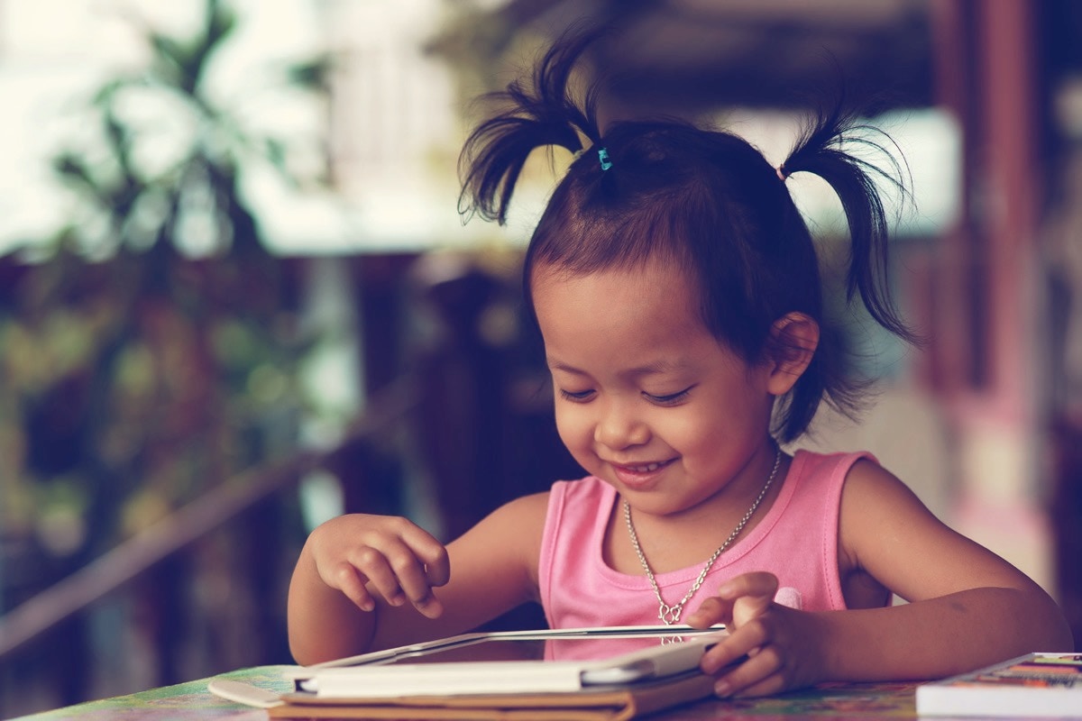 young girl looking at an ipad and smiling