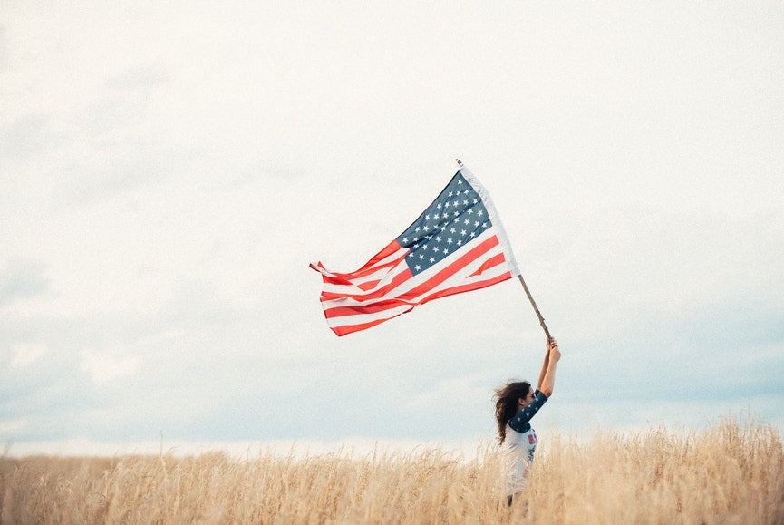 woman holding a flag in a wheat field