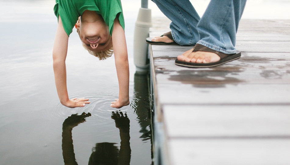man holding boy upside down boy touching the water