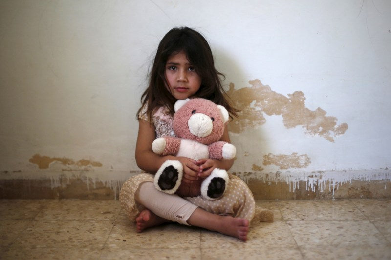 young girl holding a pink teddy bear