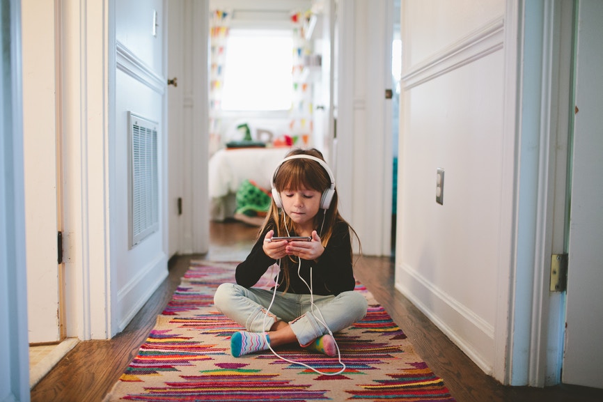 girl sitting on a rug looking at phone with earphone on