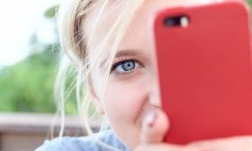 young girl with blonde hair and blue eyes holding a red phone