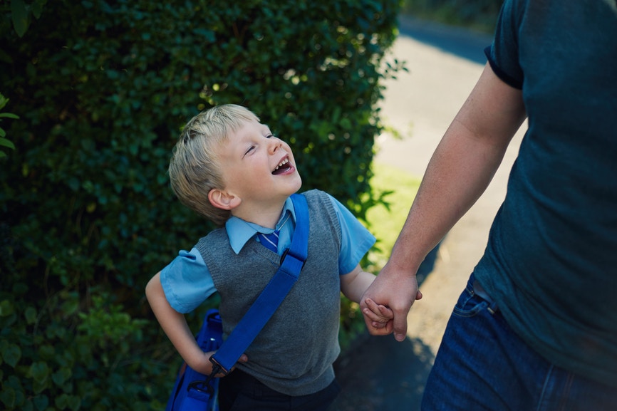 Little happy boy walking together with his father and holding his hand