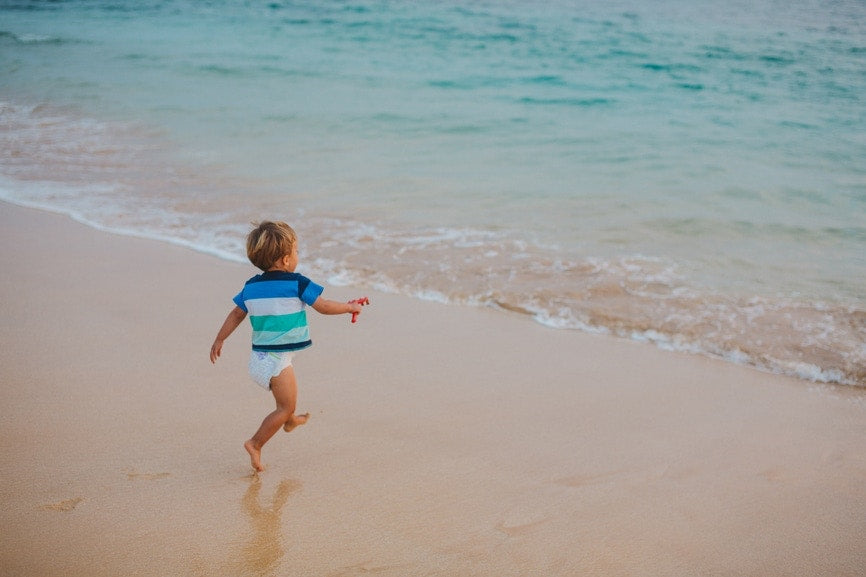 Little boy running and jumping at sea shore.