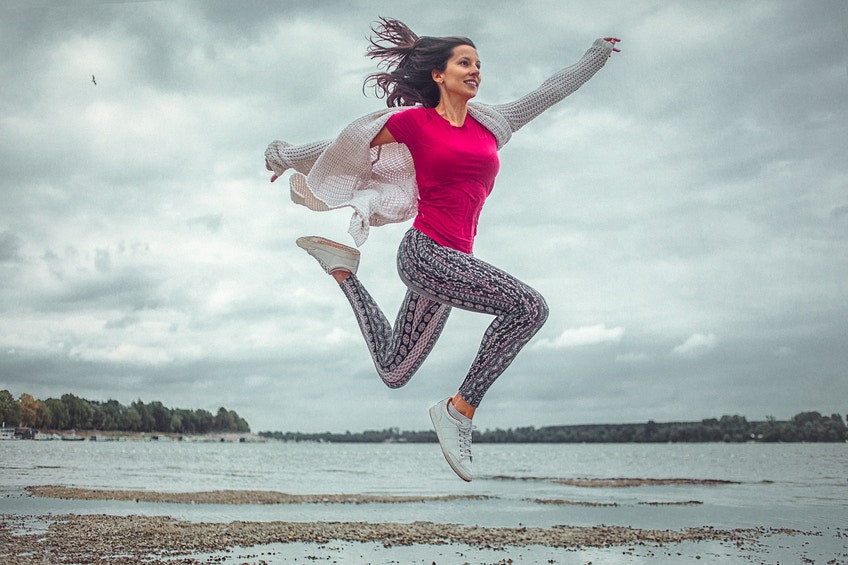 happy young woman jumping in air in front of the sea