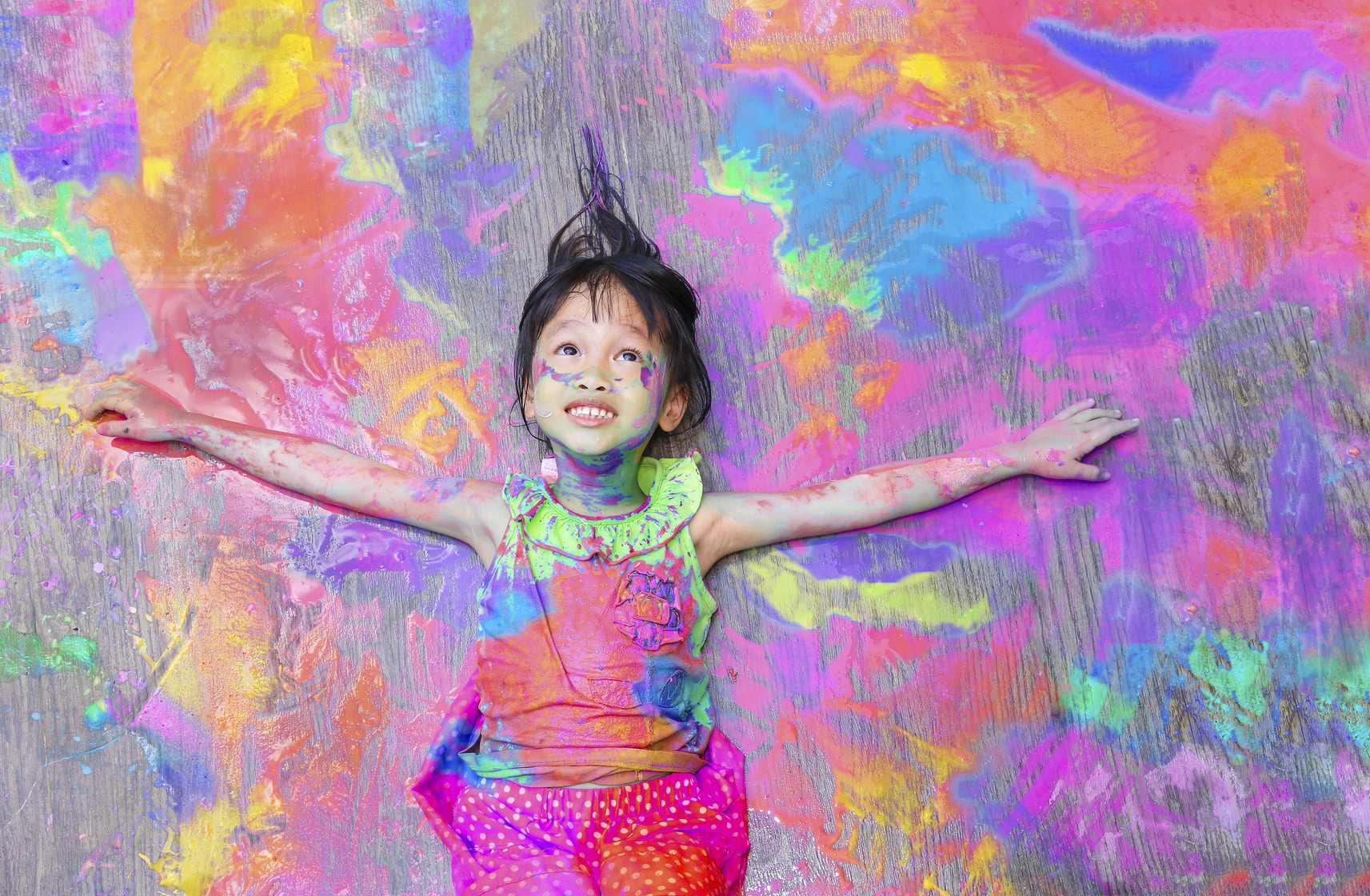 girl covered in paint lying on splattered paint background